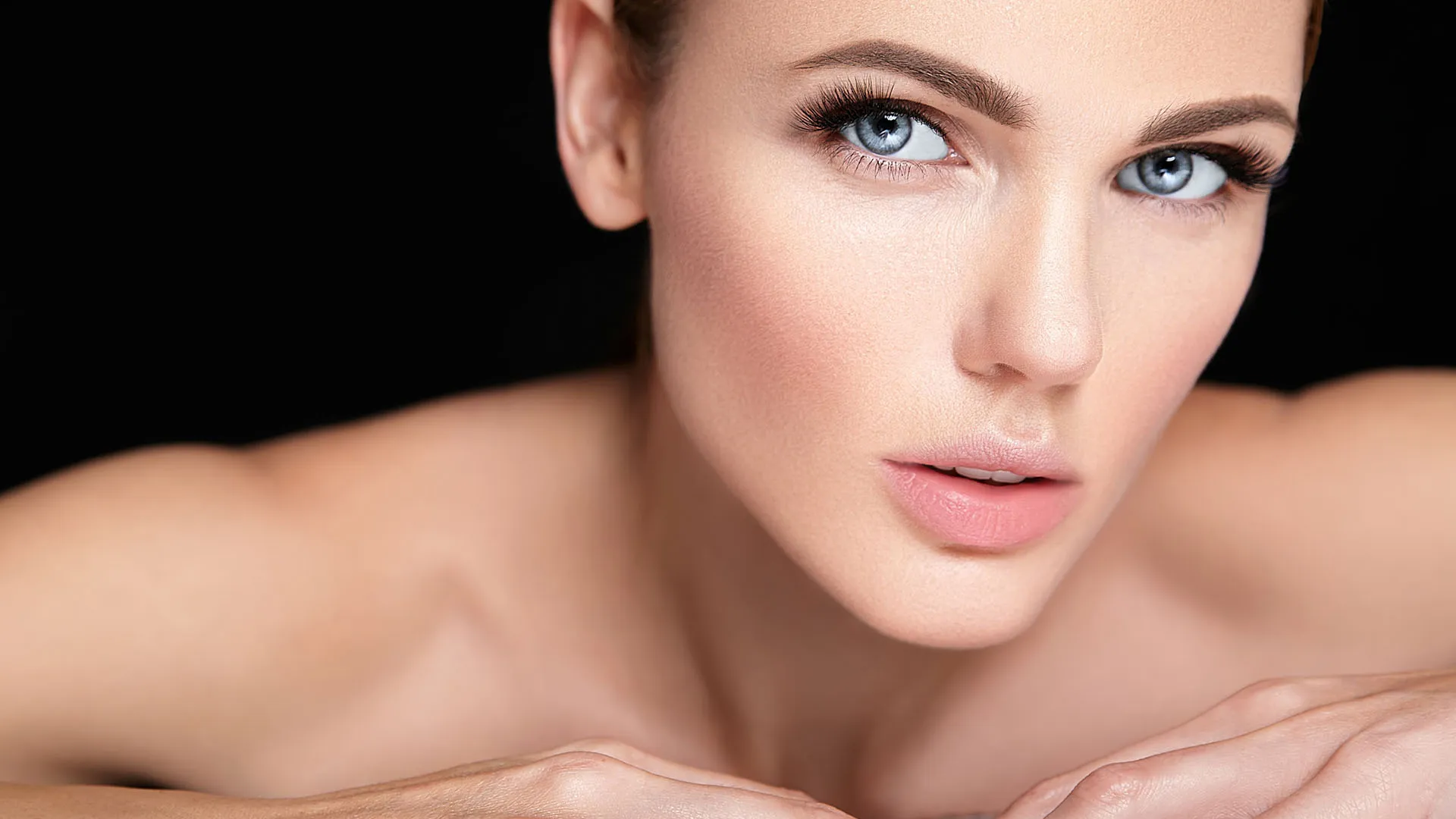 Woman with smooth, even skin resting her chin on her hands
